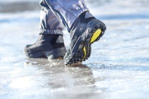 Winter legs wearing boots walking on snowy and sleet road